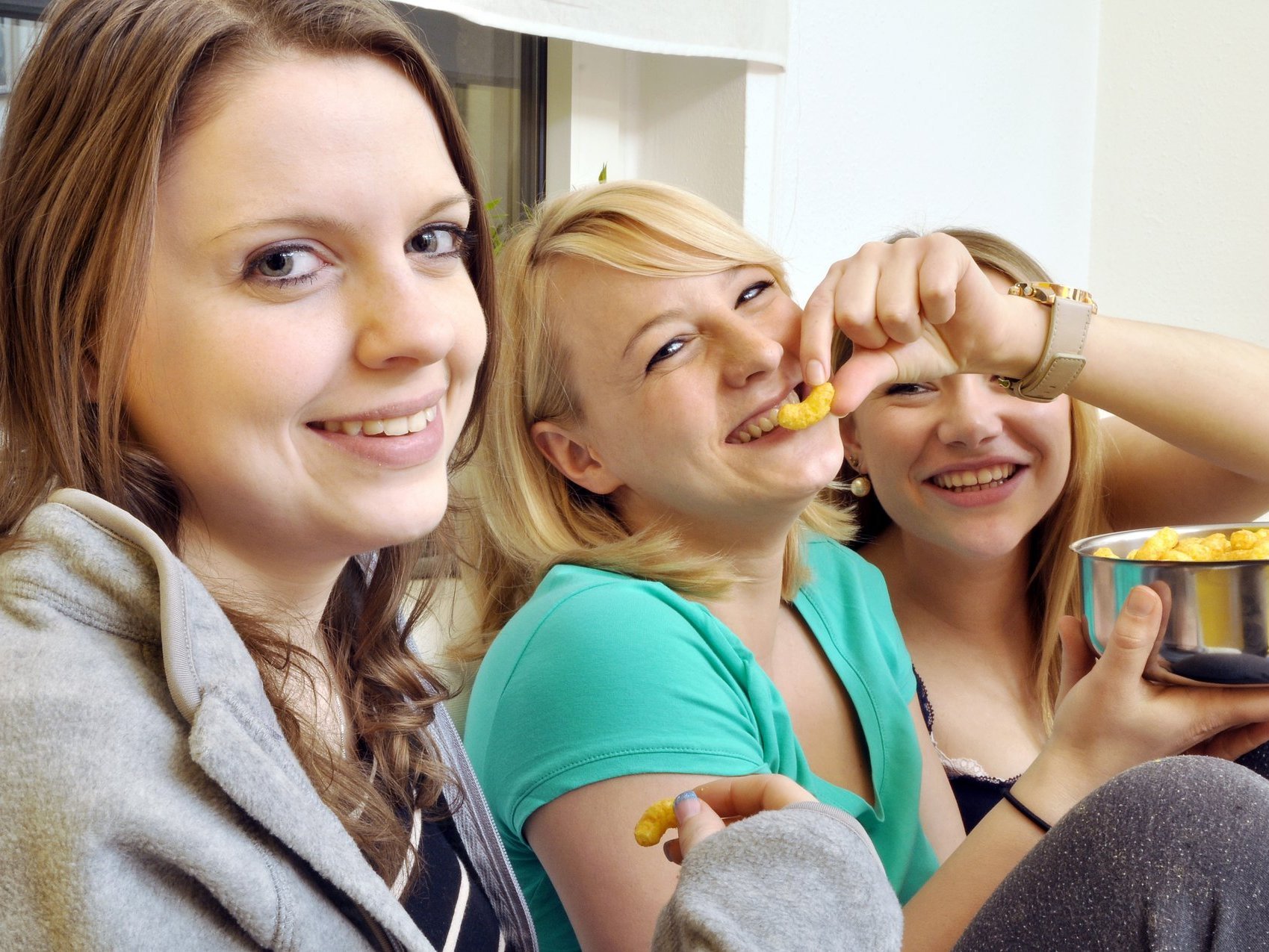 Drei junge Frauen beim Erdnuss-Flips-Essen haben Spaß
