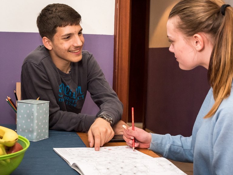 Mädchen und Junge unterhalten sich fröhlich am Tisch